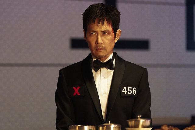 Close-up of Lee Jung Jae as Gi-hun in the new Squid Game 3 trailer, looking serious.