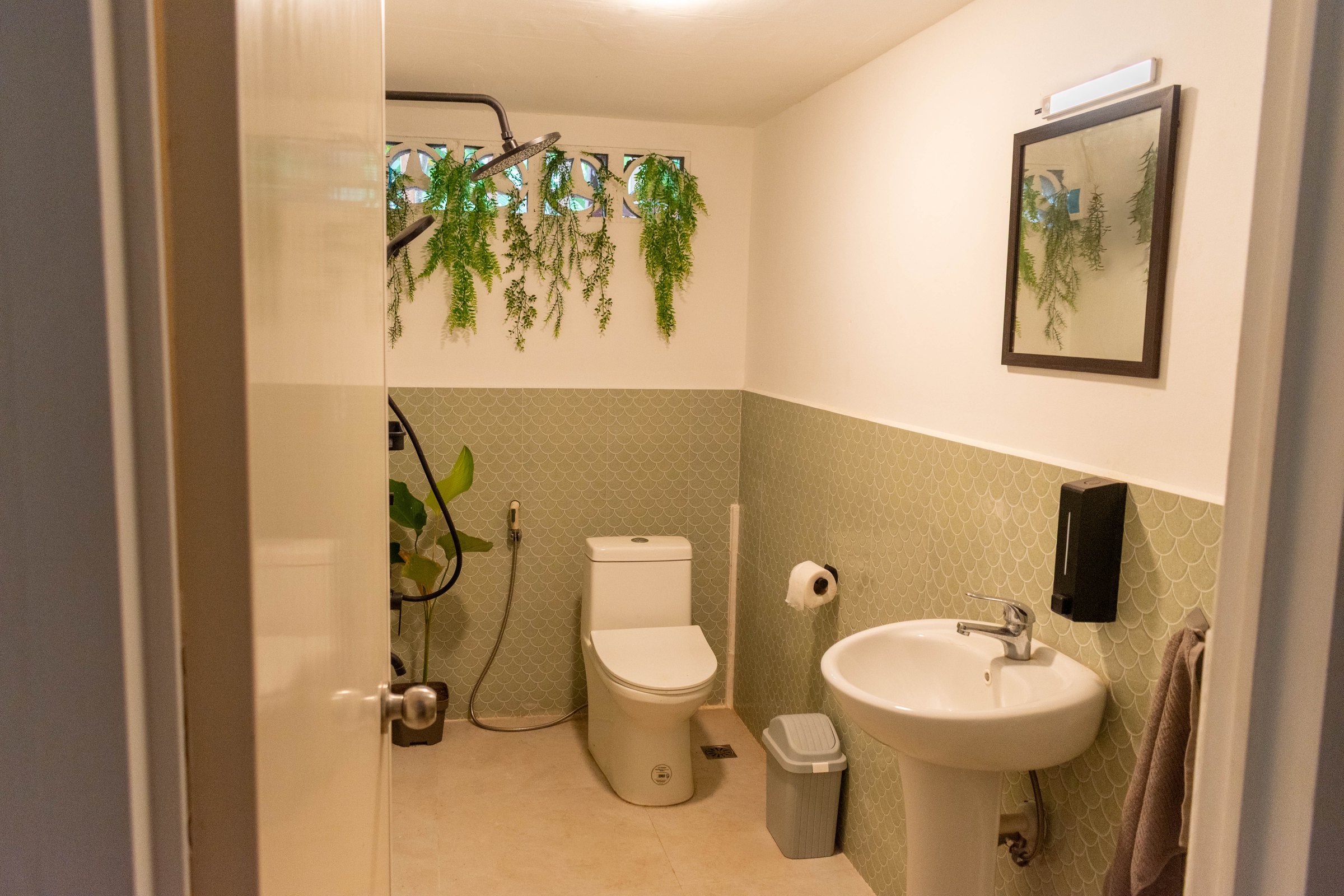Renovated bathroom with green tiles, plants and a new sink