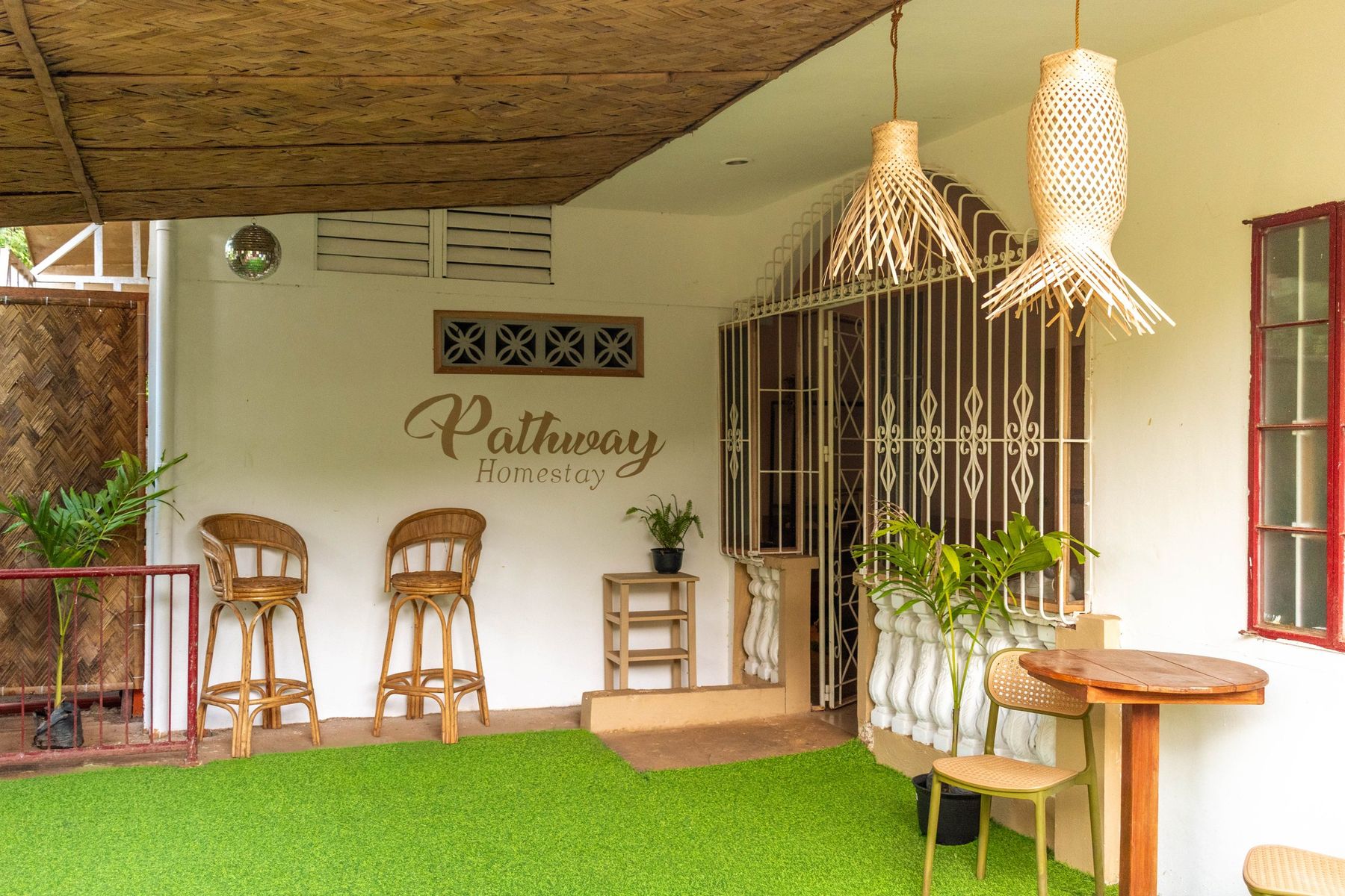 Veranda of Pathway Homestay Libis with rattan chairs and the Pathway Homestay sign