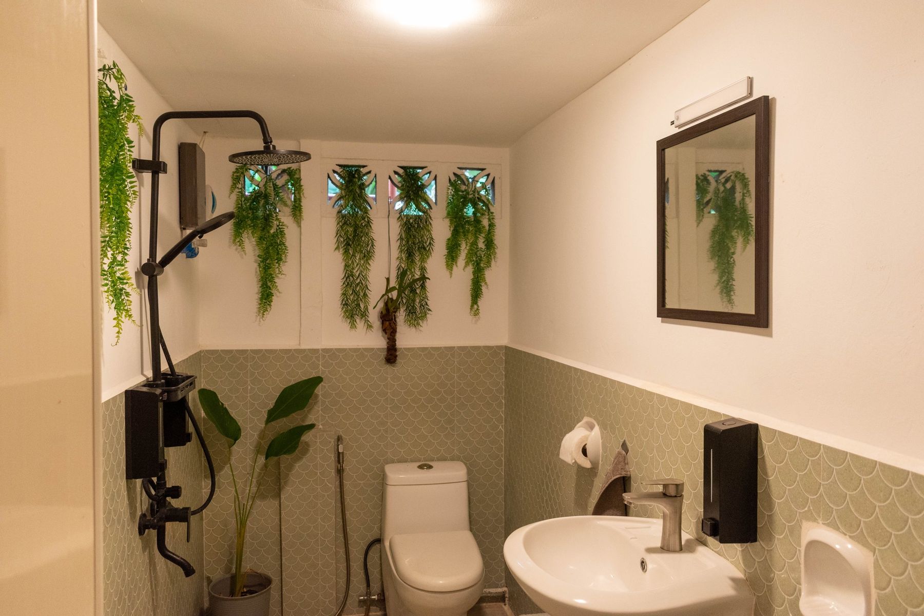 Bathroom after the renovation, green tiles, plants and a rain shower