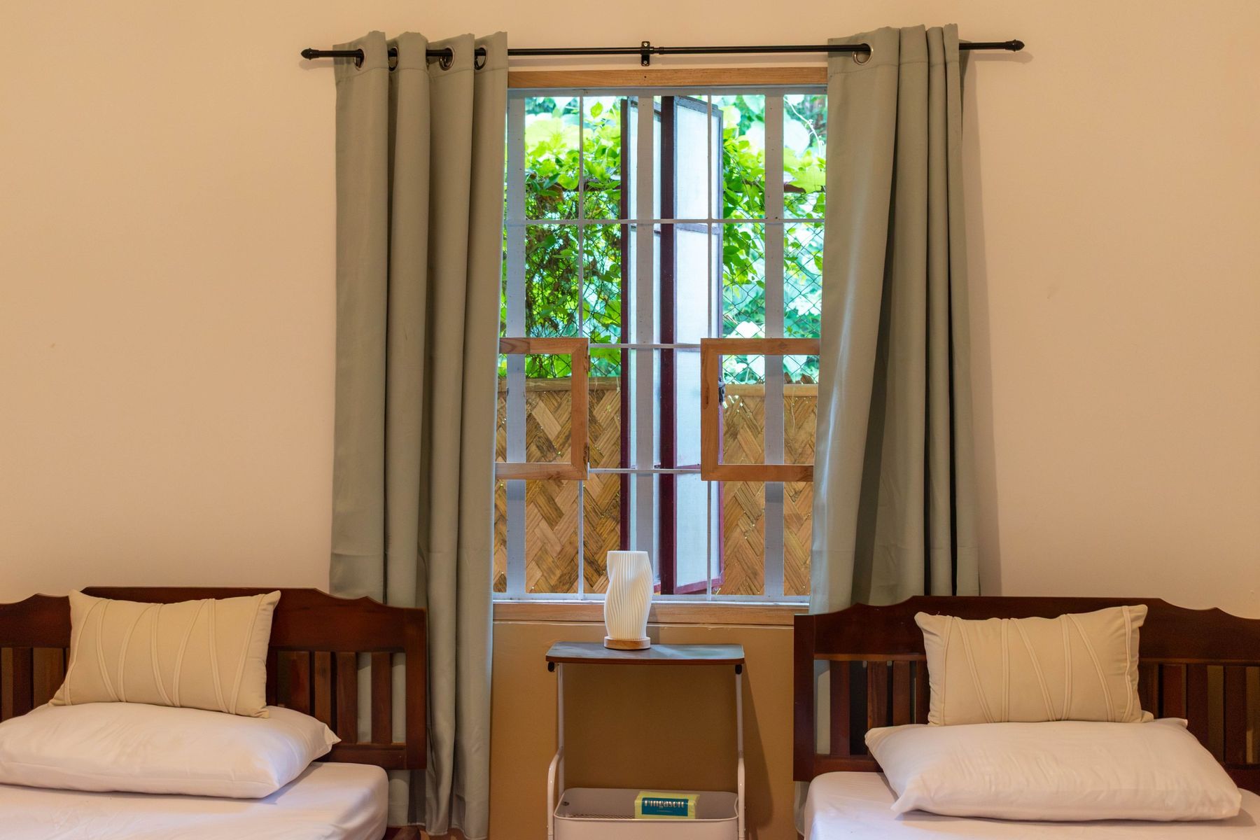 The same bedroom after the renovation, two beds with green curtains