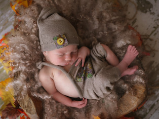 sleepy curled up newborn baby wearing romper and hat