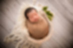 gorgeous sleeping baby boy with a brown swaddle lying in a basket