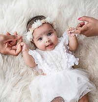 a smiling 4 month old girl holding her parents hands for her baby photoshoot in aldershot, hampshire