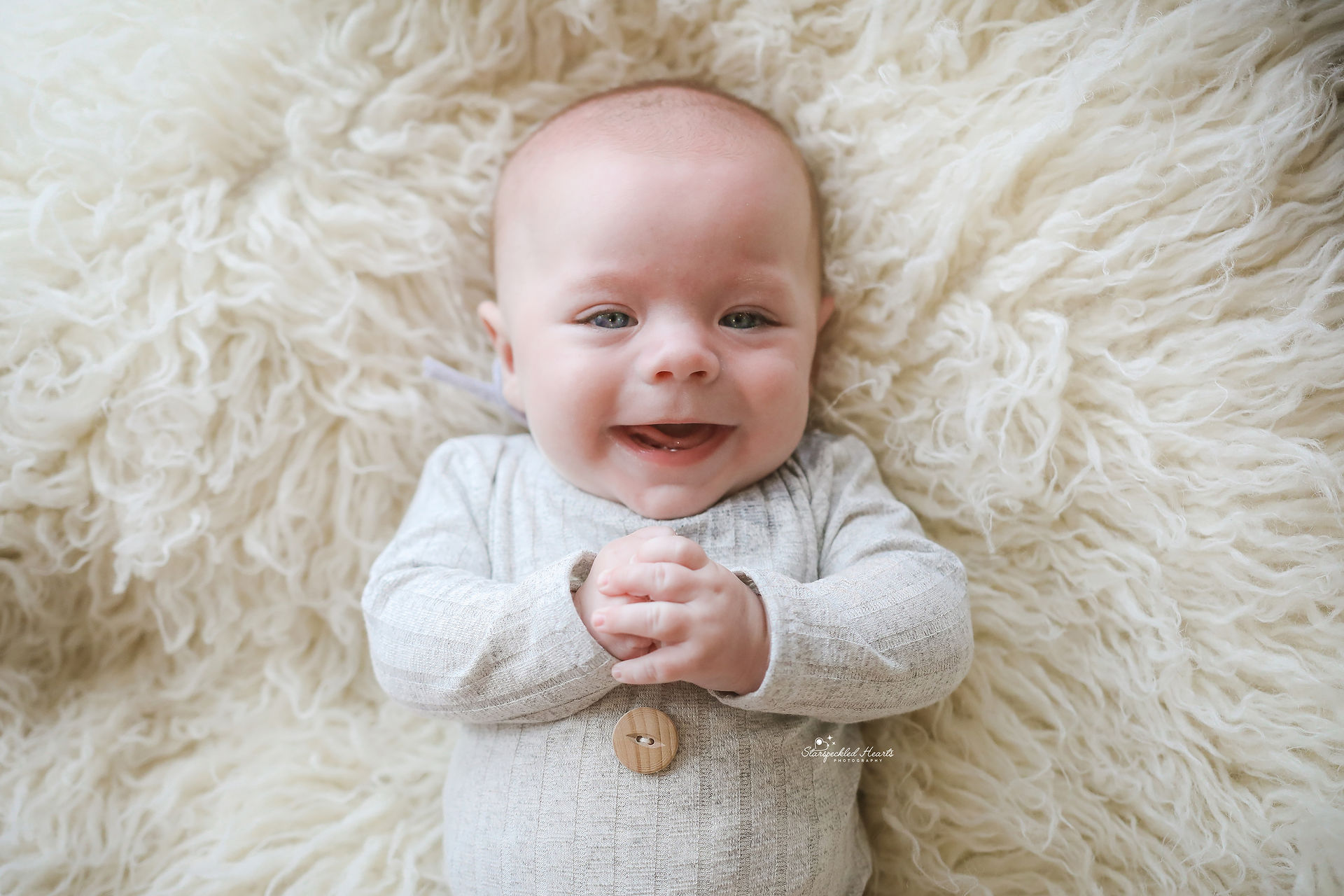 baby boy with blue eyes laying on a white rug