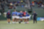 Rugby team huddling on the field during a game
