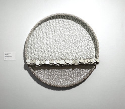 Œuvre murale circulaire et texturée de l'artiste Marie-Josée Gustave, composée de motifs entrelacés en matériaux naturels. Vue d'installation en galerie. Exposition "Couples Artistes" (2024), Fondation Jordi Bonet, Art contemporain. Commissaire : Laurent Bonet. / Circular and textured wall-mounted artwork by artist Marie-Josée Gustave, composed of interlaced patterns in natural materials. Gallery installation view. "Couples Artistes" exhibition (2024), Fondation Jordi Bonet, Contemporary Art. Curator: Laurent Bonet.