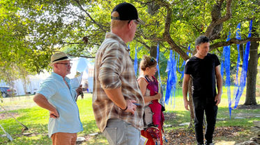 Photographie de groupe captée lors de l'événement « Land Art Urbain » (2023) montrant Claude Vallée (professeur à l'ITAQ), Marc Séguin, Jérémie Boudreault (membre du jury) et l'artiste François-René Despatis l'Écuyer. En arrière-plan, une installation textile bleue s'intègre à la canopée du Jardin Daniel A. Séguin. Fondation Jordi Bonet, Art contemporain. Commissaire : Laurent Bonet. / Group photograph taken during the "Land Art Urbain" event (2023) featuring Claude Vallée (ITAQ Professor), Marc Séguin, Jérémie Boudreault (Jury member), and artist François-René Despatis l'Écuyer. In the background, a blue textile installation integrates with the canopy of Jardin Daniel A. Séguin. Fondation Jordi Bonet, Contemporary Art. Curator: Laurent Bonet.