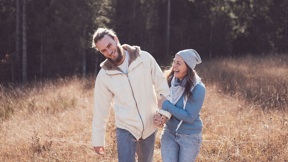 Lachendes glückliches Paar auf einer herbstlichen Wiese im Wald