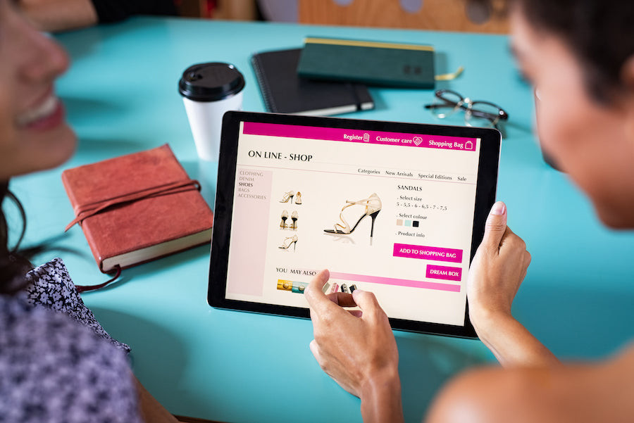 two woman looking at shoes on a tablet