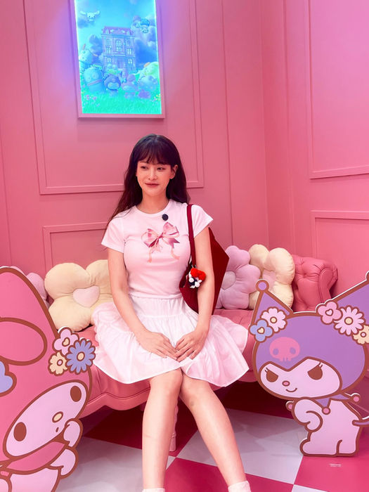 Woman in pink dress posing with My Melody and Kuromi