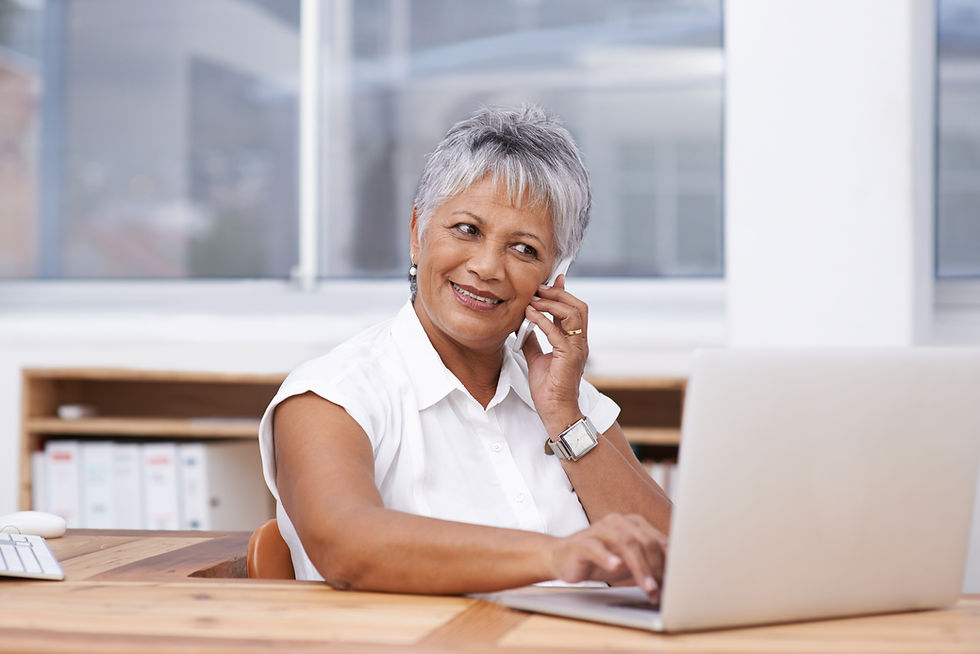Business woman multitasking at her desk by talking on the phone and looking at her computer
