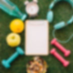 An image of some barbells, water bottle, headphones, a healthy snack, some fruit and a clipboard.