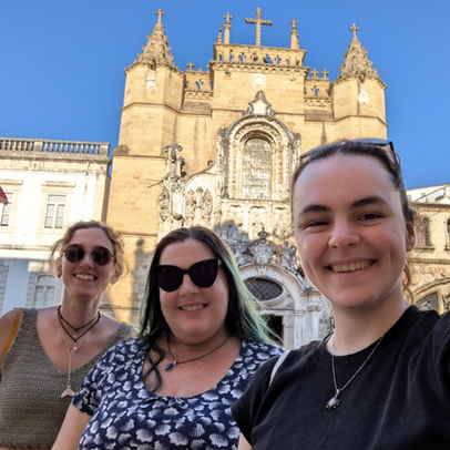 Three people smiling in front of the university in Coimbra