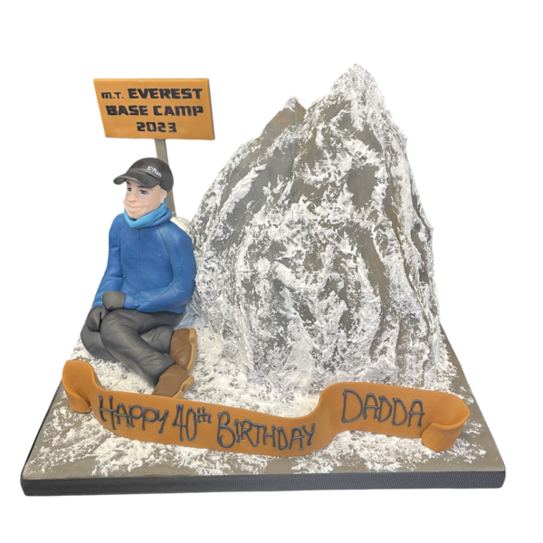 A cake decorated to resemble a mountain climber conquering Mt Everest, featuring snowy peaks, ropes, and climbing gear, ideal for adventurous celebrations.