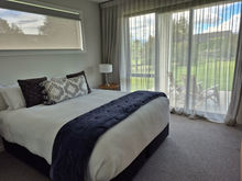 Bedroom with King size bed, chest of drawers, NZ wool carpet, 2 bedside tables & lamps. This one also has a wall mounted Smart TV.