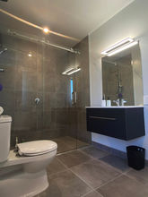 This ensuite bathroom has two entrances and serves two bedrooms. It comprises a roomy shower, vanity unit and toilet.