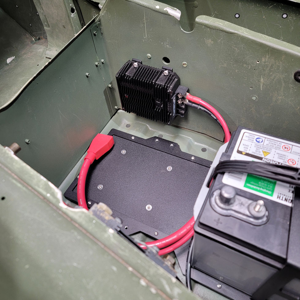 24V-to-12V converter installed in a Humvee's battery compartment, wired to the battery.