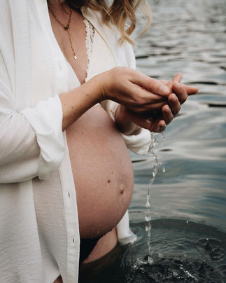 Schwangere Frau im Wasser, die Wasser in ihren Händen hält.