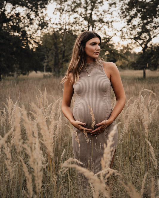 Schwangere Frau im beigen Kleid steht in hohem Grasfeld bei Sonnenuntergang Golden Hour Shooting Frankfurt, Schwangerschaft Frankfurt