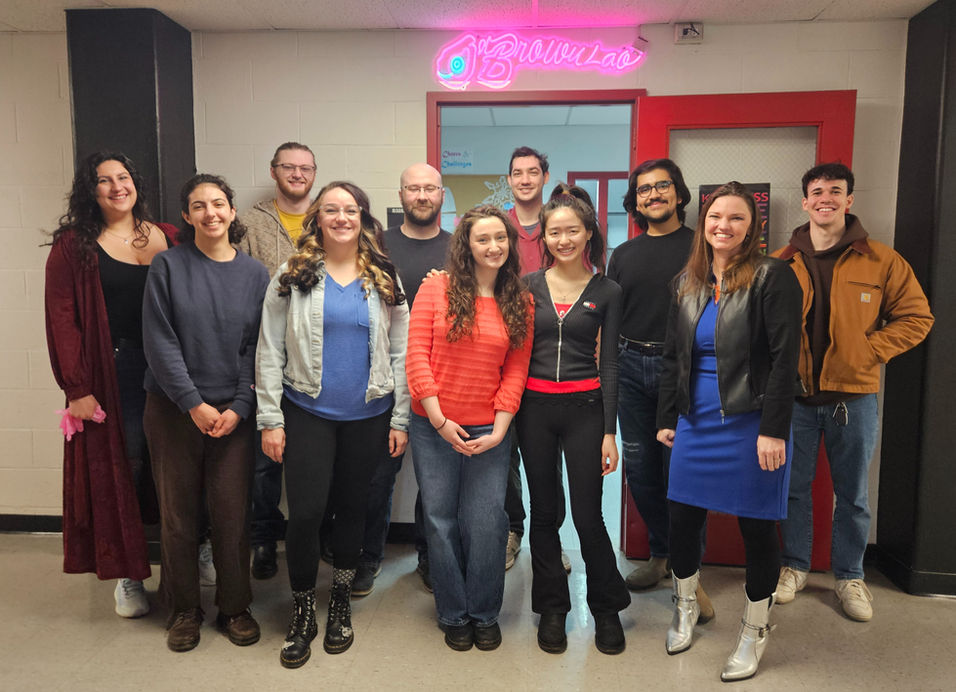 Group photo of the O'Brown lab under our signature neon sign