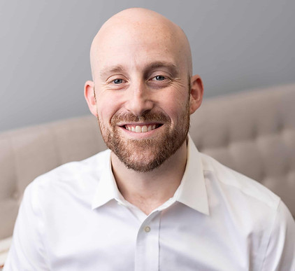 Drew Schafer, an OCD and anxiety therapist at Mid Michigan Therapy, smiling in his office.