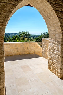 Stone archway overlooking trees, stairs and sky