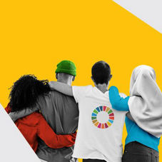 Imagen de cuatro personas de espaldas, abrazadas, frente a un fondo amarillo vibrante. Una de ellas viste una camiseta blanca con el logotipo circular de los Objetivos de Desarrollo Sostenible (ODS). La imagen simboliza la unidad global y el compromiso humano hacia la sostenibilidad y la acción climática.