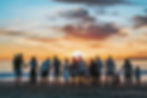 A group holding hands on the beach at sunset