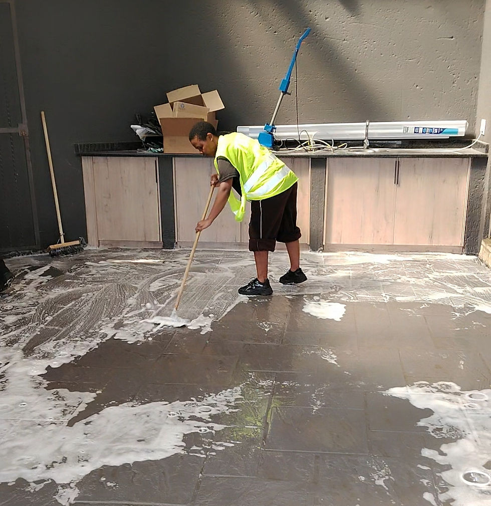 Worker performing shanela cleaning services, scrubbing a wet floor