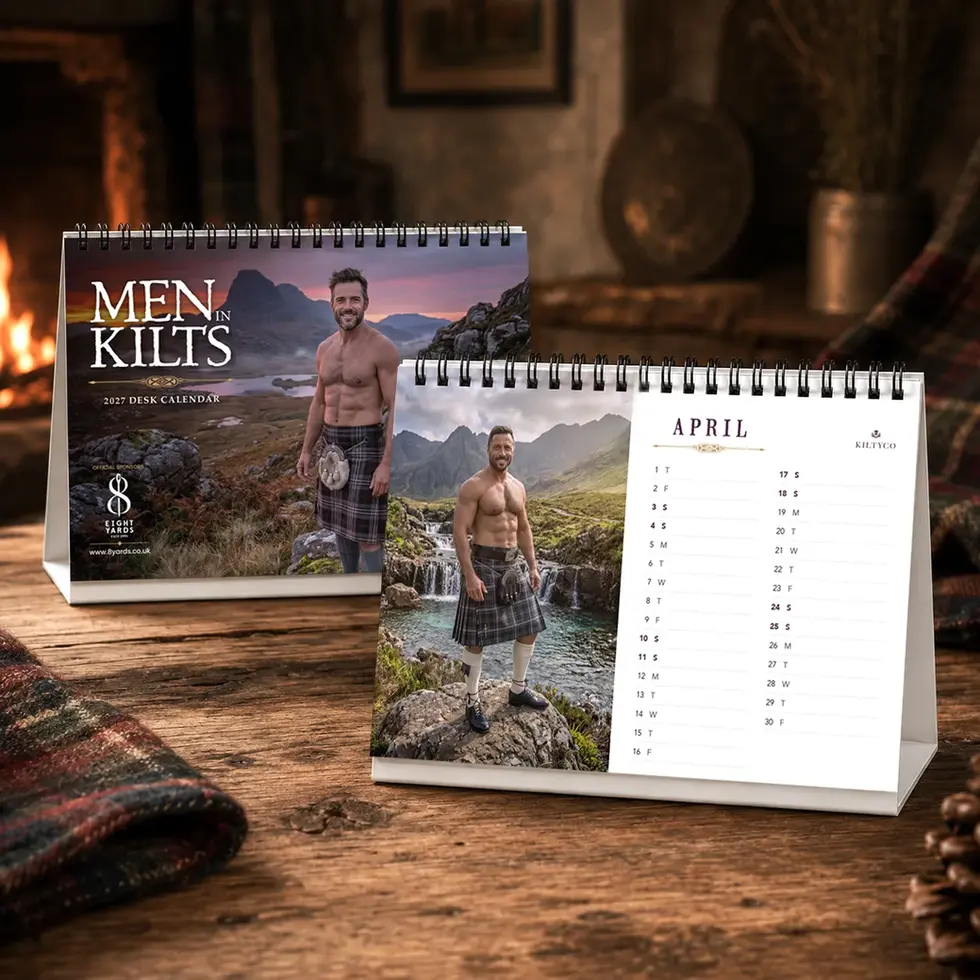 Men in Kilts Calendar 2027 A6 desk calendar cover and internal monthly page displayed on a rustic desk
