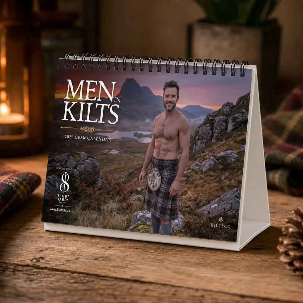 Men in Kilts A6 Desk Calendar 2027 displayed on a rustic wooden desk