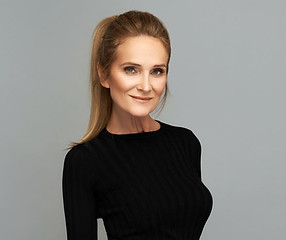 A confident, mature woman with smooth skin, a defined jawline, and a natural expression. Clean gray background, soft lighting, and subtle makeup — ideal to represent facial rejuvenation, tightening, and lifting.