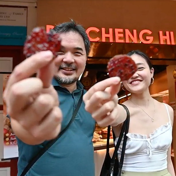 Tourists holding Bak Kwa Coins in front of Bee Cheng Hiang, Singapore