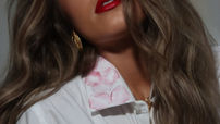 A girl in a mens white dress shirt with red lipstick stains on the collar.