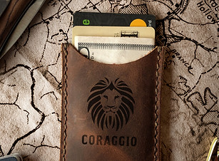 A dark brown leather card holder with the CORAGGIO Lion logo on the front. 