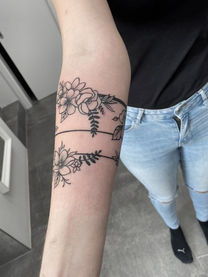 Arm with floral tattoo art, two black lines, flowers. PICTURES FINE LINE TATTOO.