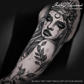 Dark tattoo of woman with moon and floral headpiece, Austrian Perfection since 2003.