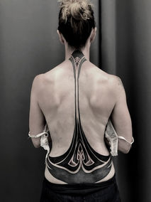 Rear view of the woman with a large, geometric tattoo on her back. Andre Zechmann