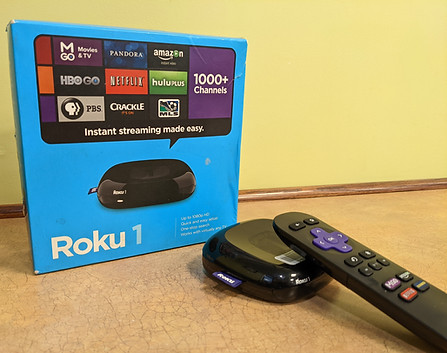 The blue box for a Roku beside the small black machine itself with its black remote.