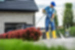 A man in blue overalls and yellow boots cleans a driveway with a pressure washer, surround