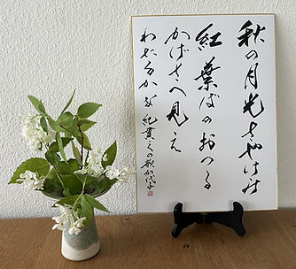 Japanische Kalligraphie eines Waka-Gedichts auf Shikishi-Papier mit weissen Blumen