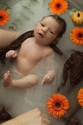 bébé enveloppé dans un lange photographié dans un bain de lait fleuri