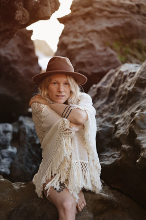 Portrait assis dans une faille rocheuse à Anglet, chapeau et châle en crochet blanc
