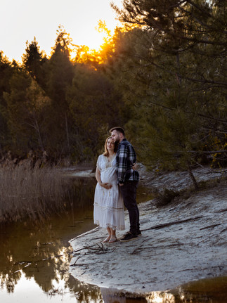 couple enlacé prés d'un lac au coucher du soleil avec maman enceinte