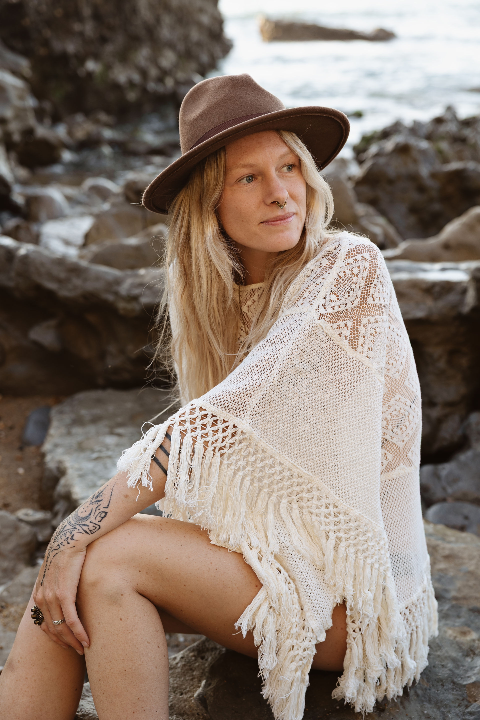 Portrait assis dans une faille rocheuse à Anglet, chapeau et châle en crochet blanc