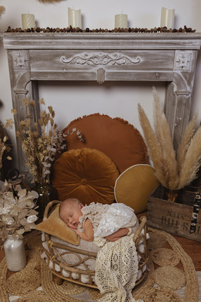 Nouveau-né couché dans un panier en rotin dans une robe et un décor bohème