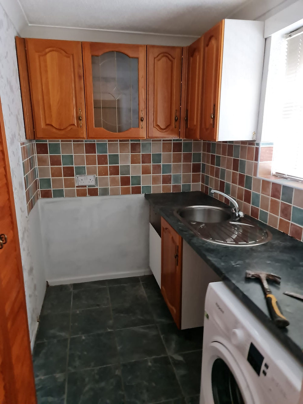 Kitchen with tiled backsplash, wood cabinets, and tools for building maintenance.