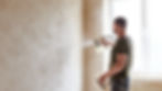 Professional painter using a spray gun to apply paint evenly on an interior wall