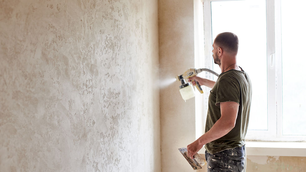 Professional painter using a spray gun to apply paint evenly on an interior wall